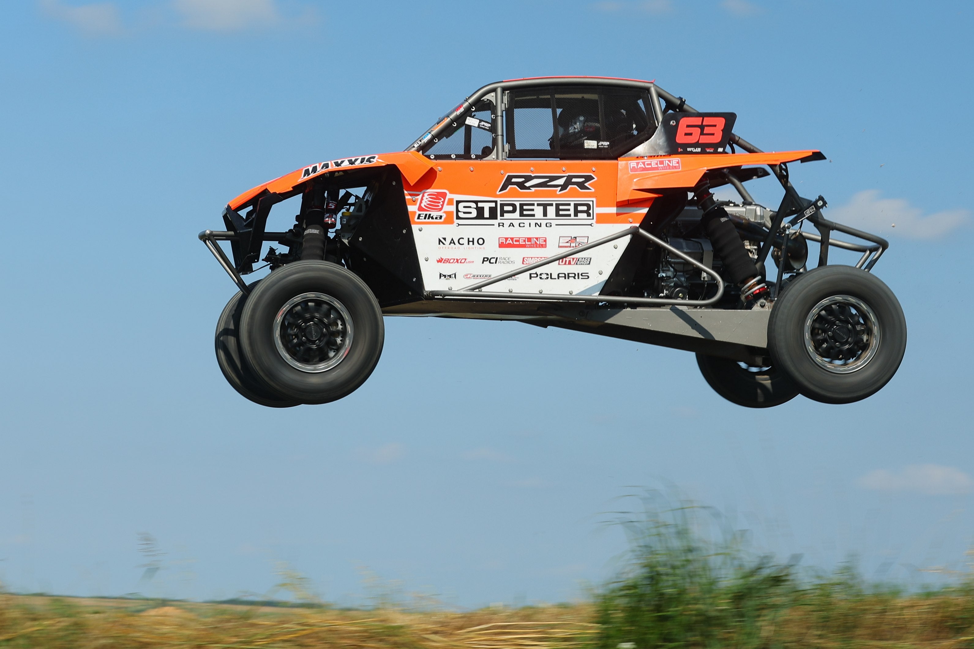 Orange number 63 side-by-side airborne during a race