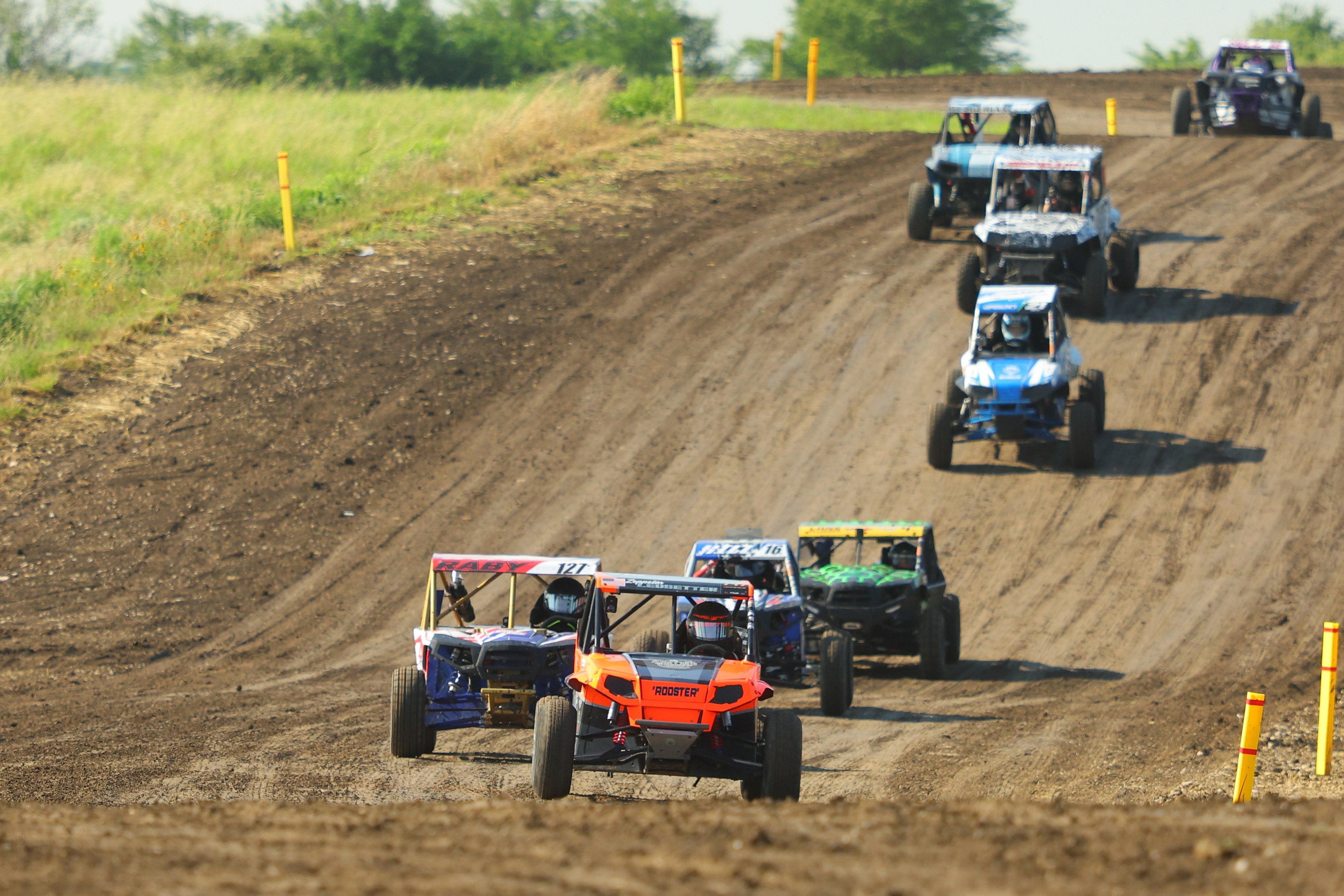Side-by-side racers charging down a dirt track