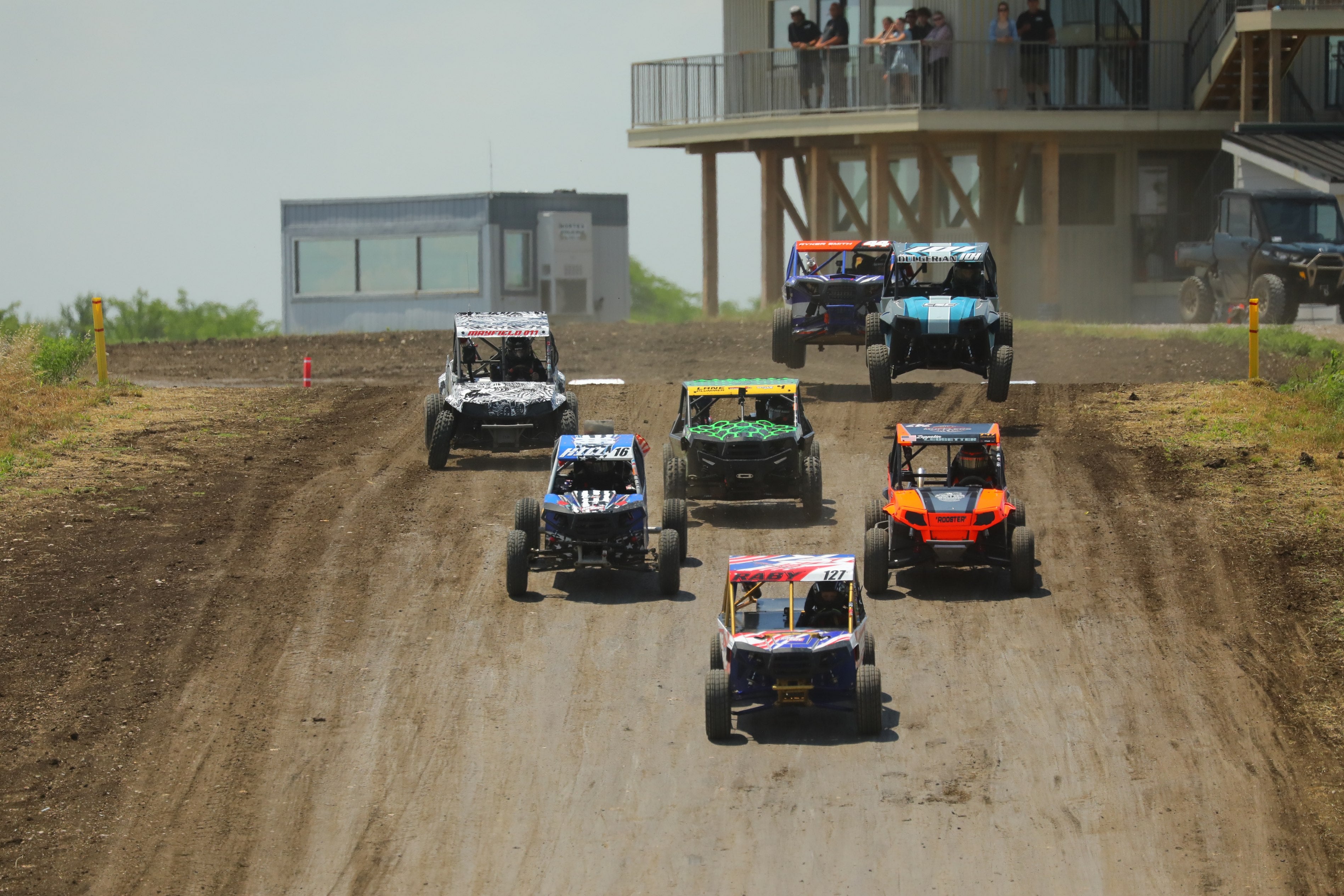 Side-by-side racers cresting a hill during competition