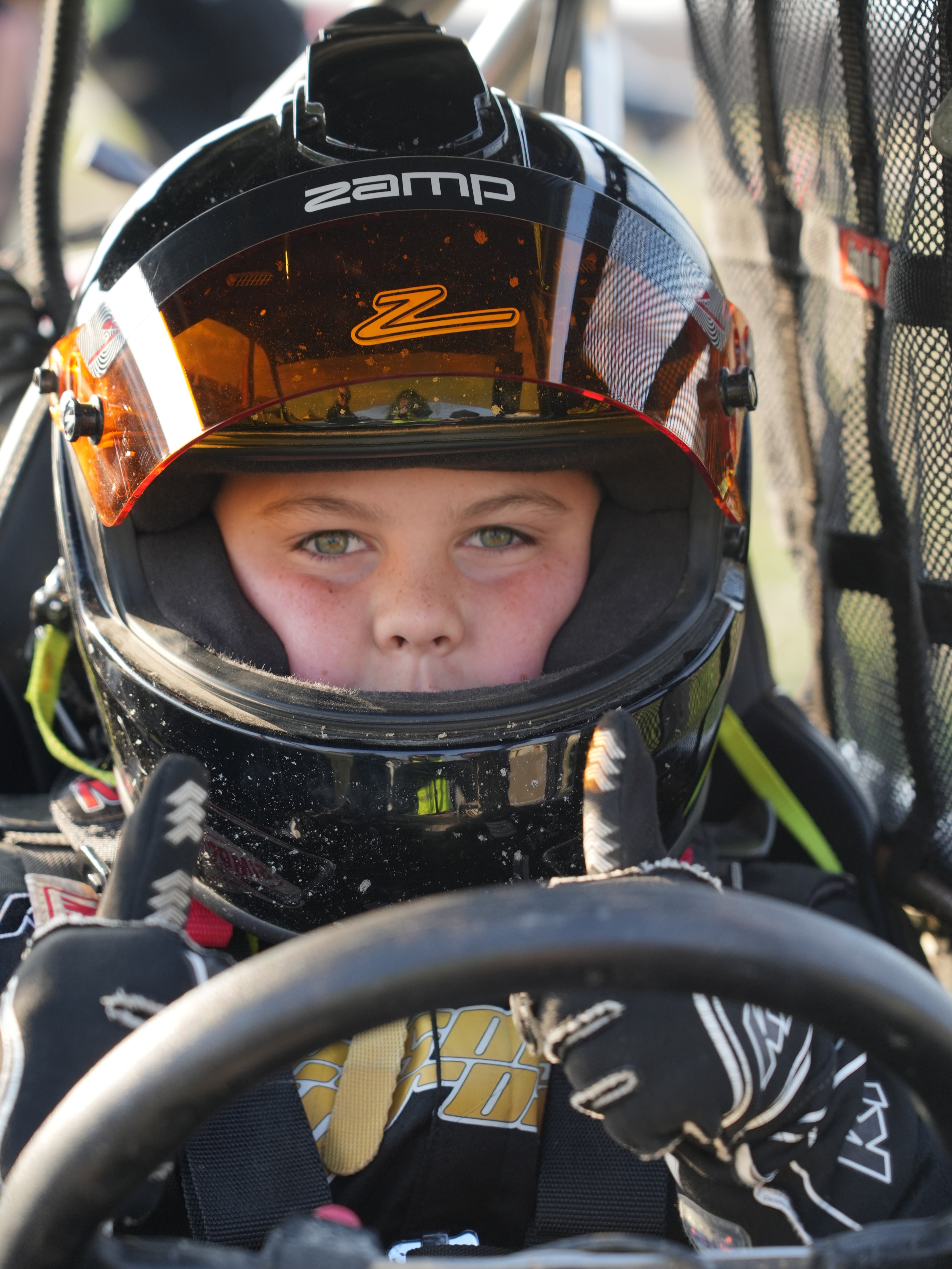 Young racer focused behind the wheel in a full-face helmet