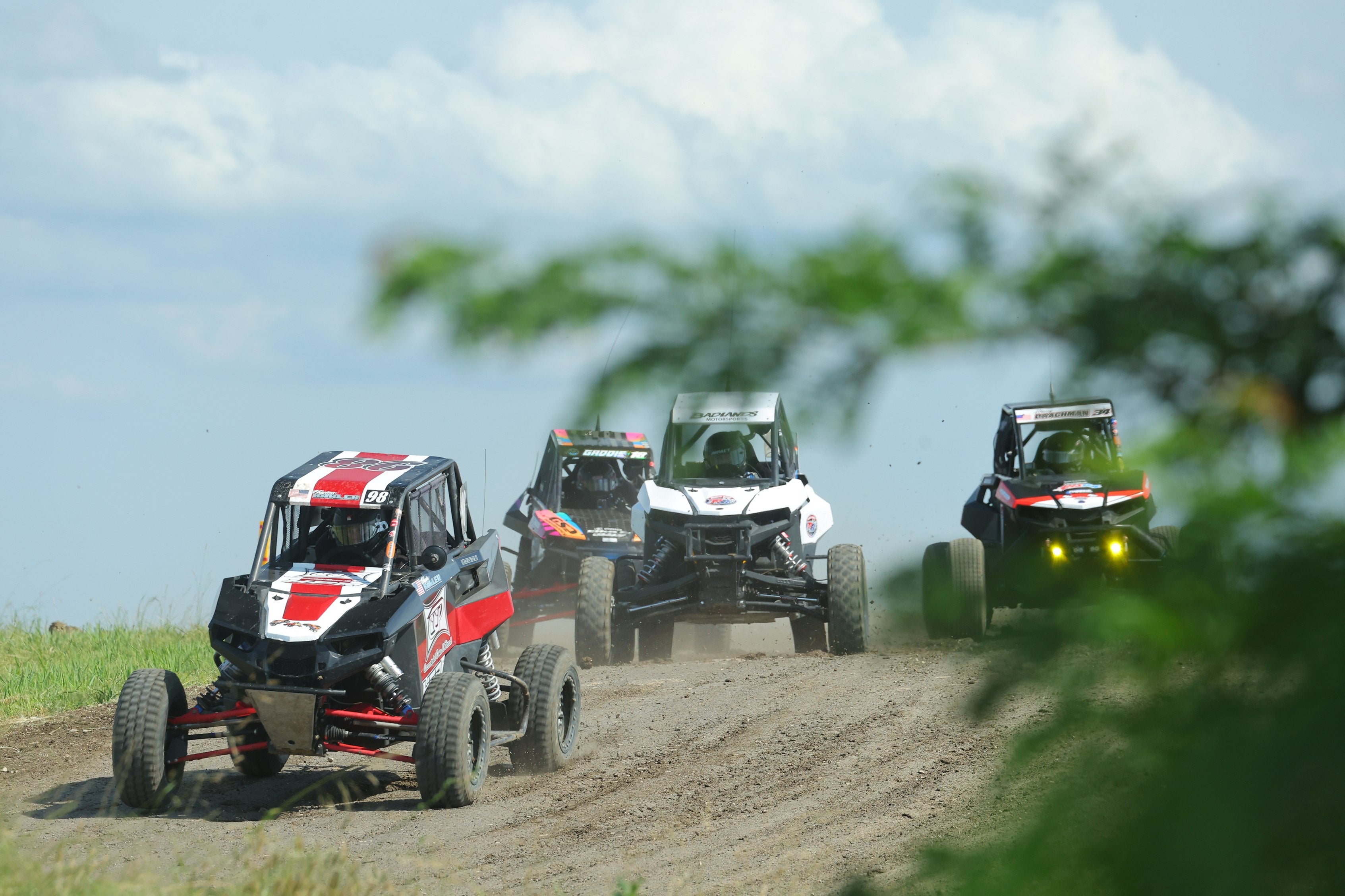 Four side-by-sides racing through a dirt course